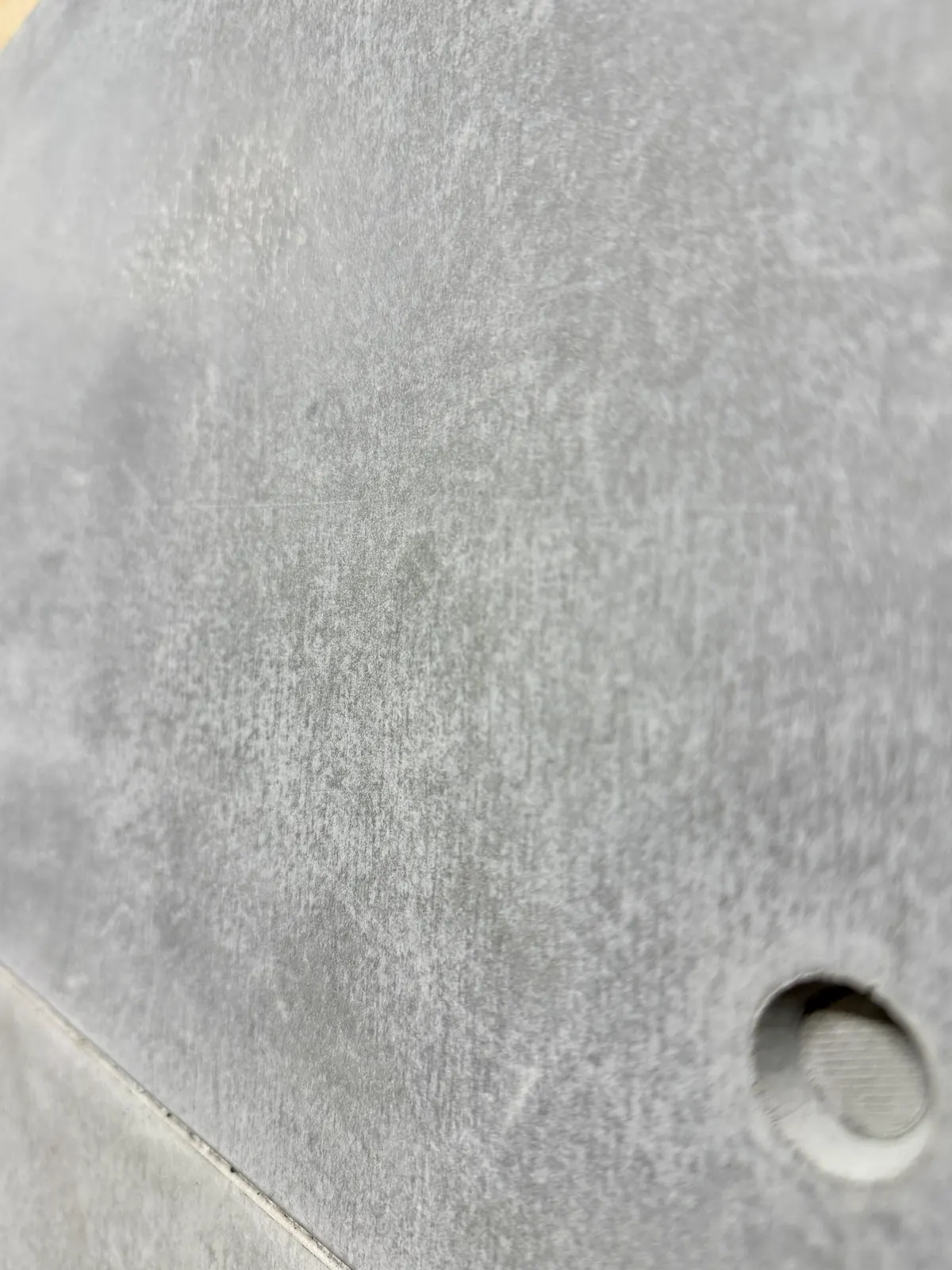 Close-up of the cast finish and fixing hole on a dark grey ROKA concrete cladding tile