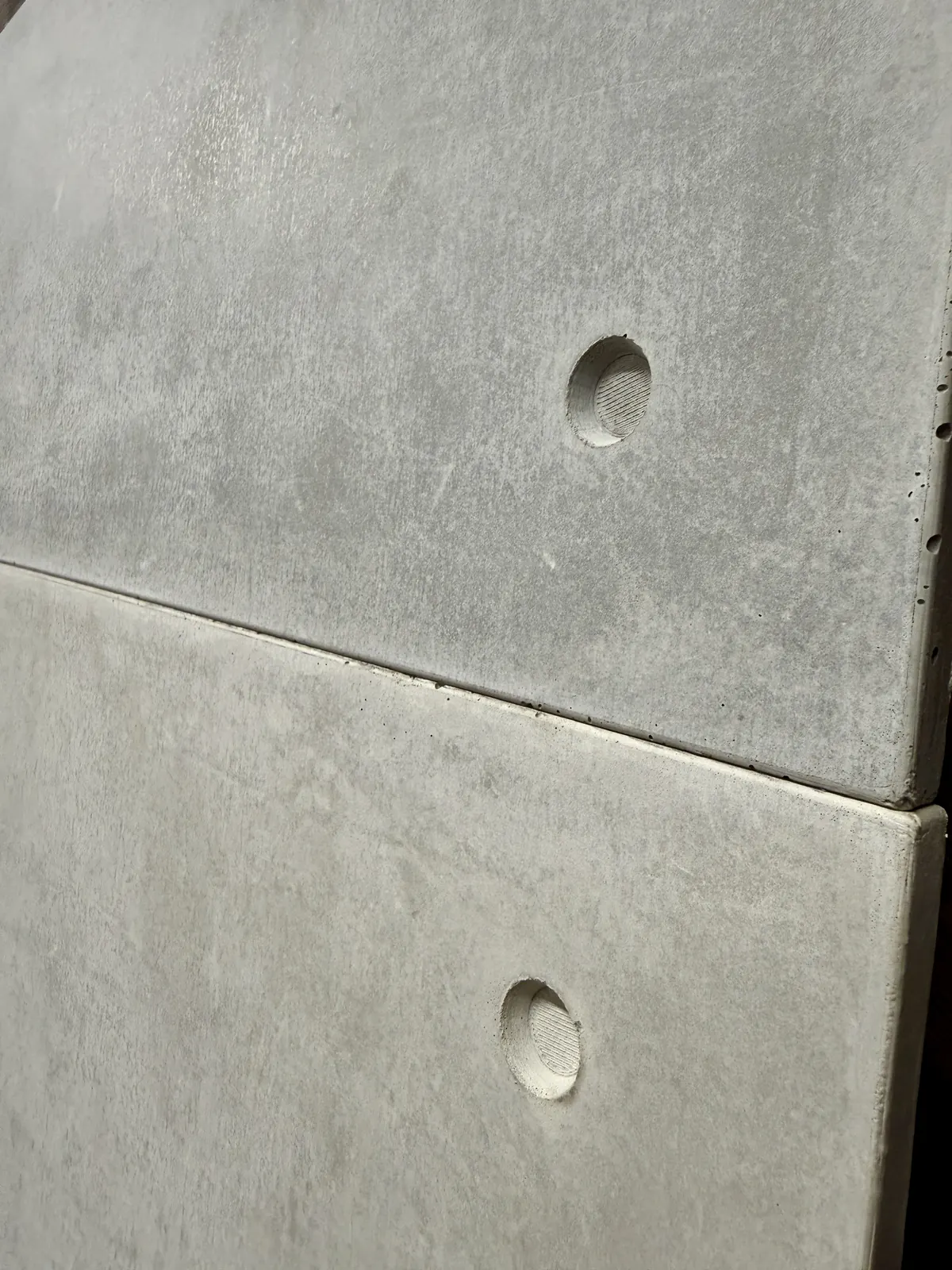 Joint between two cast concrete cladding tiles, showing edge and fixing hole